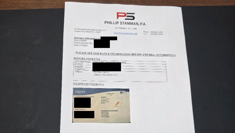 A Phillip Stamman, P.A. letterhead billing sheet on a desk, listing the client's auto insurance as primary and a Cigna health insurance card as secondary, with the client's personal information blacked out