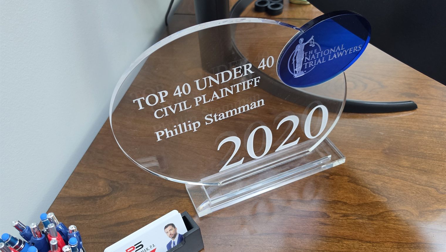 The National Trial Lawyers Top 40 Under 40 Civil Plaintiff award for 2020, engraved with Phillip Stamman's name, sitting on his desk beside his business cards